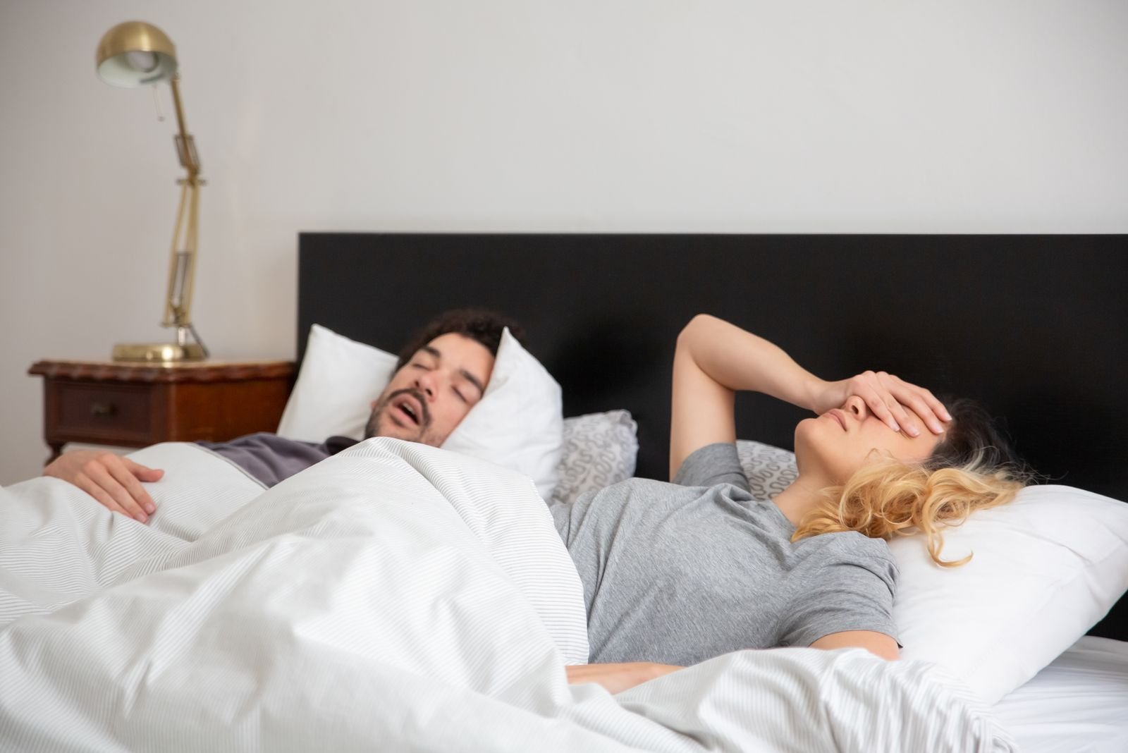 Couple in bed, one partner disturbed by snoring